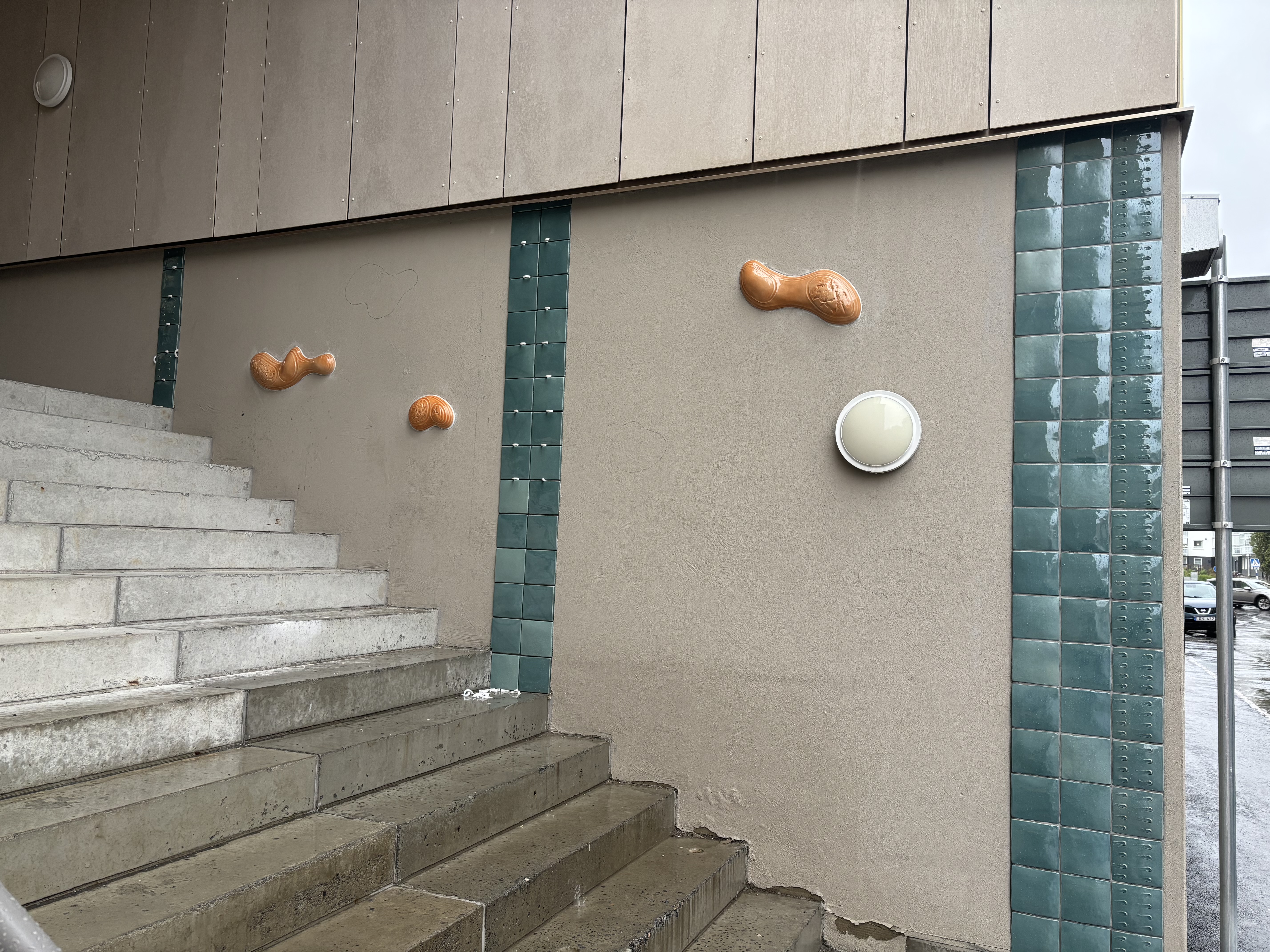 Konstverk på vägg intill betongtrappa som leder upp till innergård i bostadsområde