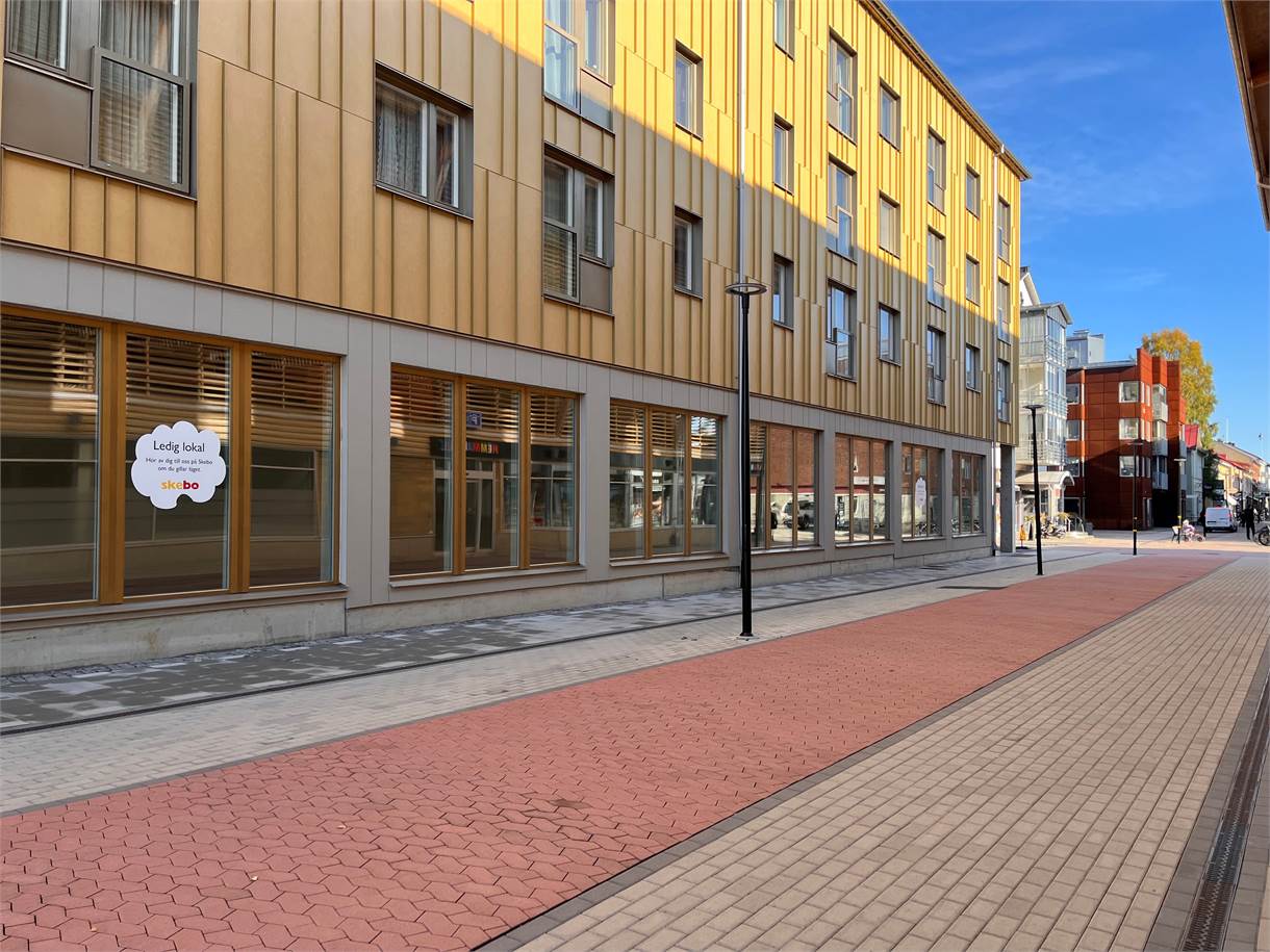 En gul byggnad längs gågata med stenbeläggning