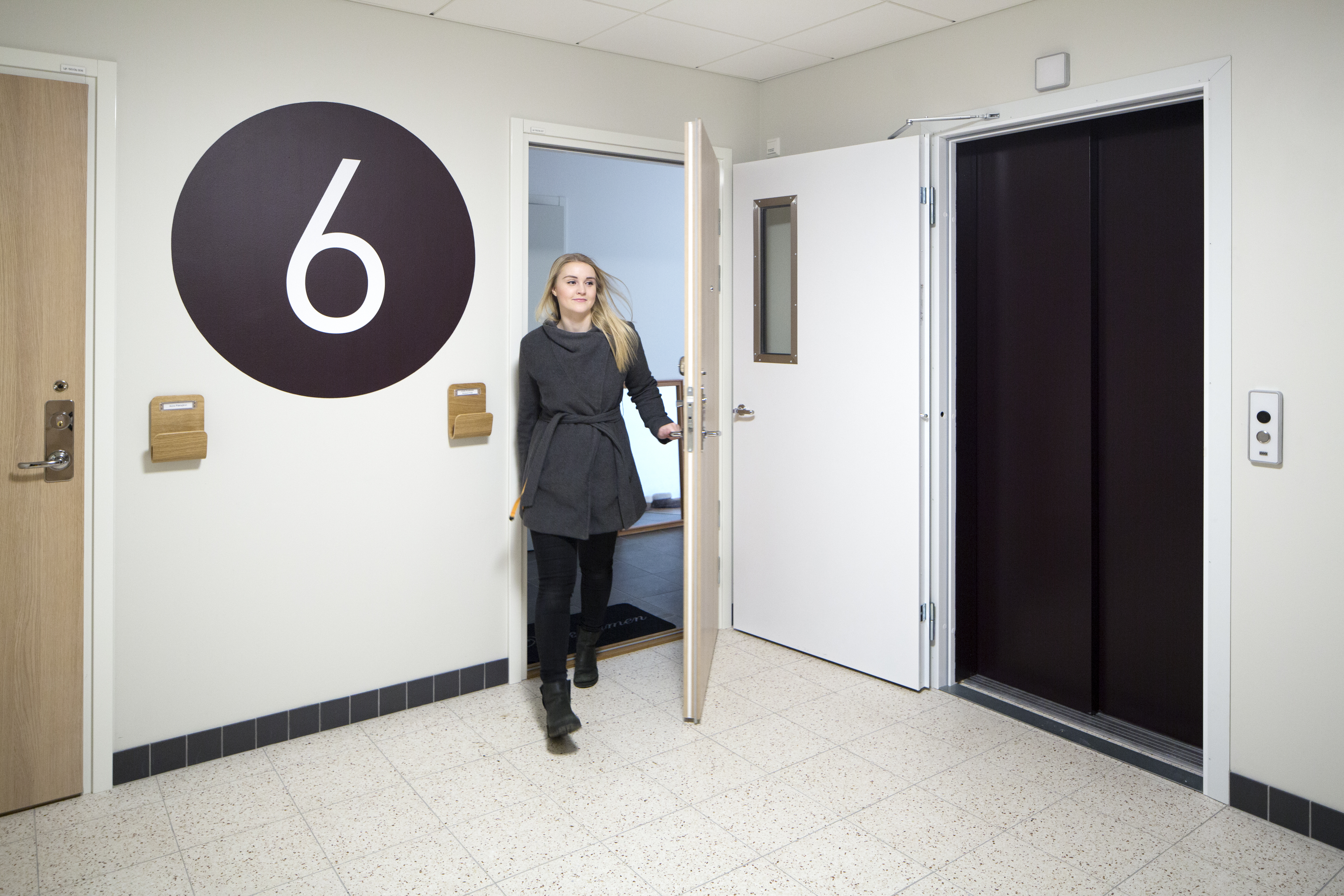 Visar en tjej som kommer ut i trapphuset från sin lägenhet