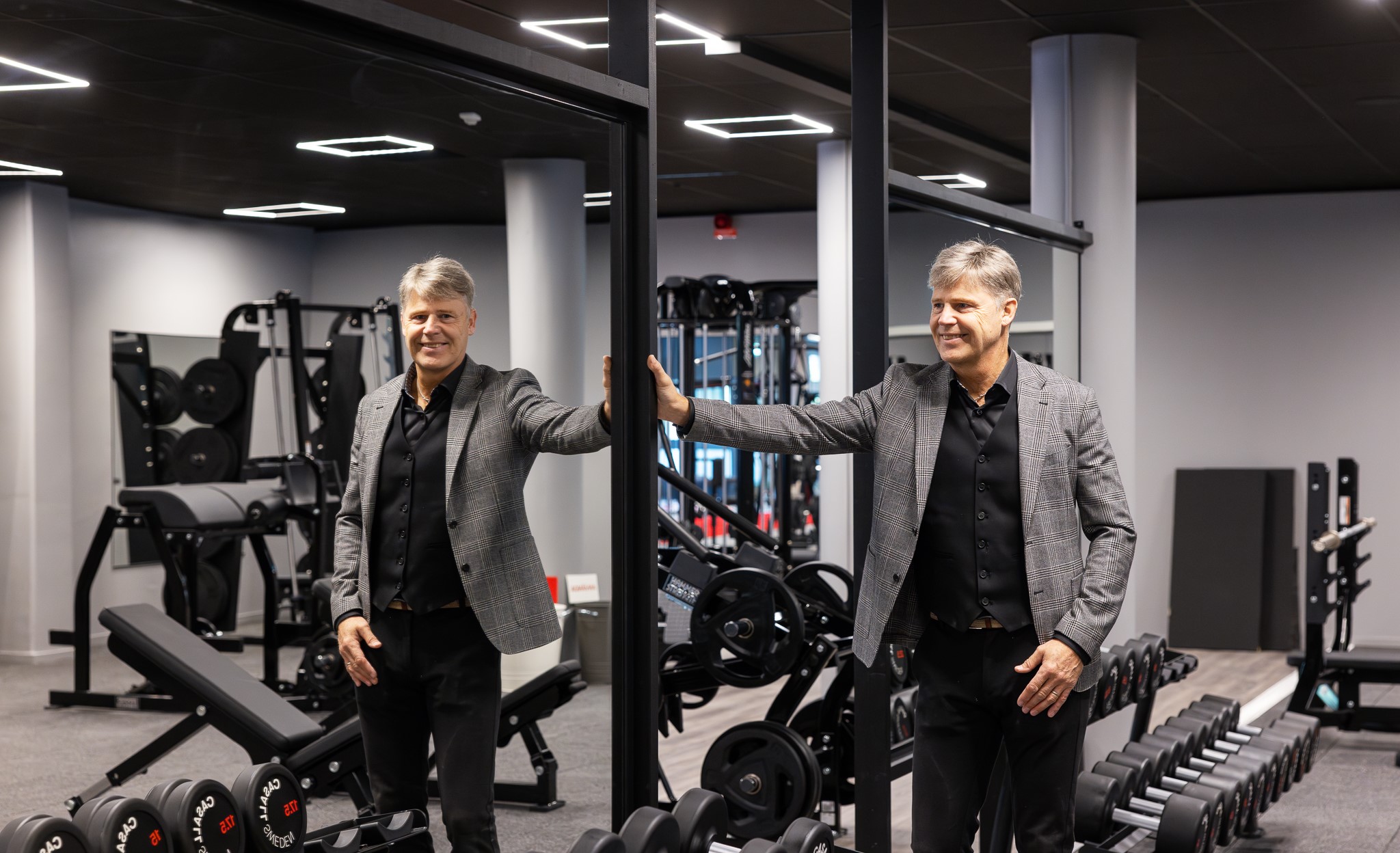 Visar en man i kavaj vid en spegelvägg i en gymlokal