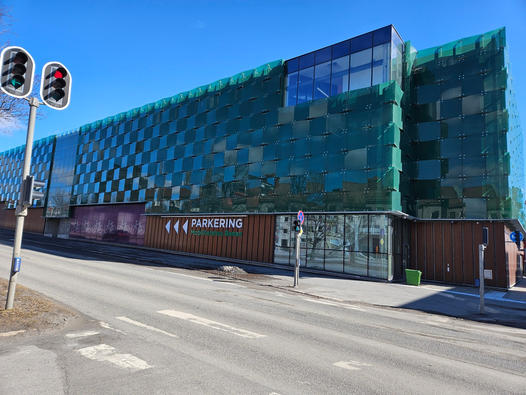 Grönt parkeringshus vid gata med trafikljus