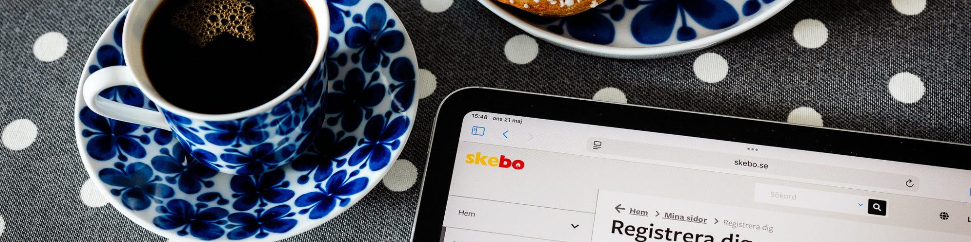 Kaffe, kanelbullar och surfplatta på ett prickigt bord